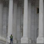 Neoclassical architecture of Capitol Building in Washington, DC, with security presence.